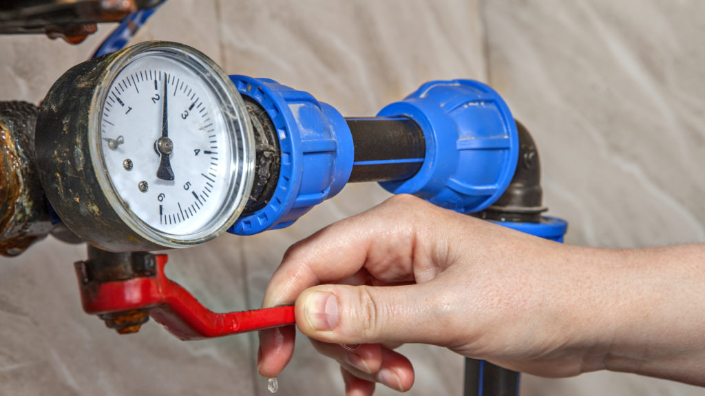 hand on a water meter checking the water pressure with a tool for home maintenance 