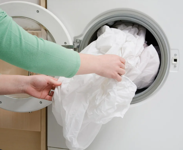 clothes being put into a washing machine 