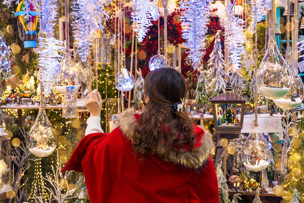 A young girl in a red coat looking at Christmas decorations