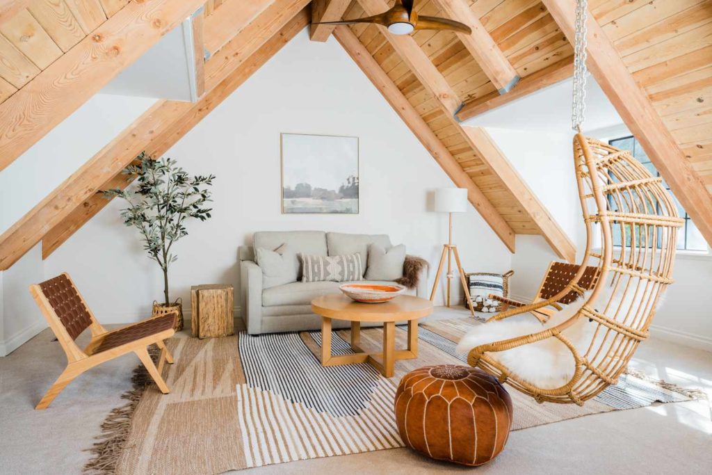An attic space that is set up as a living space, it has exposed wood tressing and beams.