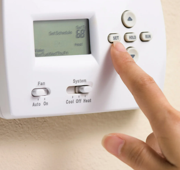 A girl is testing out the thermostats and setting schedule of heat to 68 every weekdays. 
