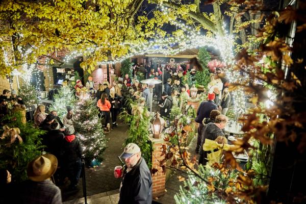 people gathered in an outdoor market at night with lights all around