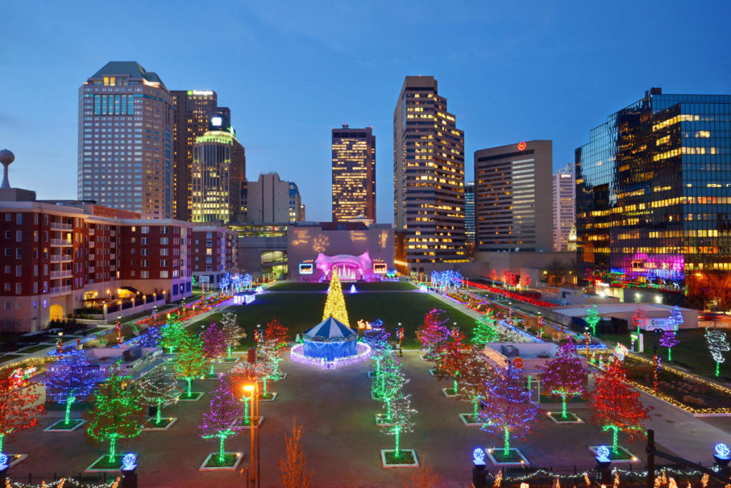 Christmas lights on trees in a park with a merry go round in the middle 