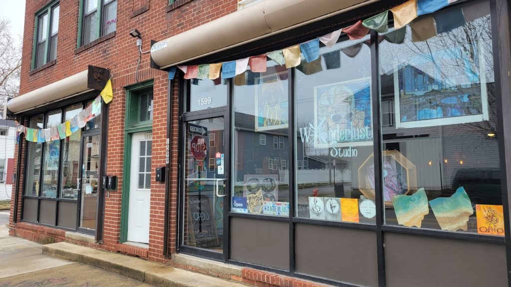 A glass store with a paint frame display and also with party hangging flags outside the store.